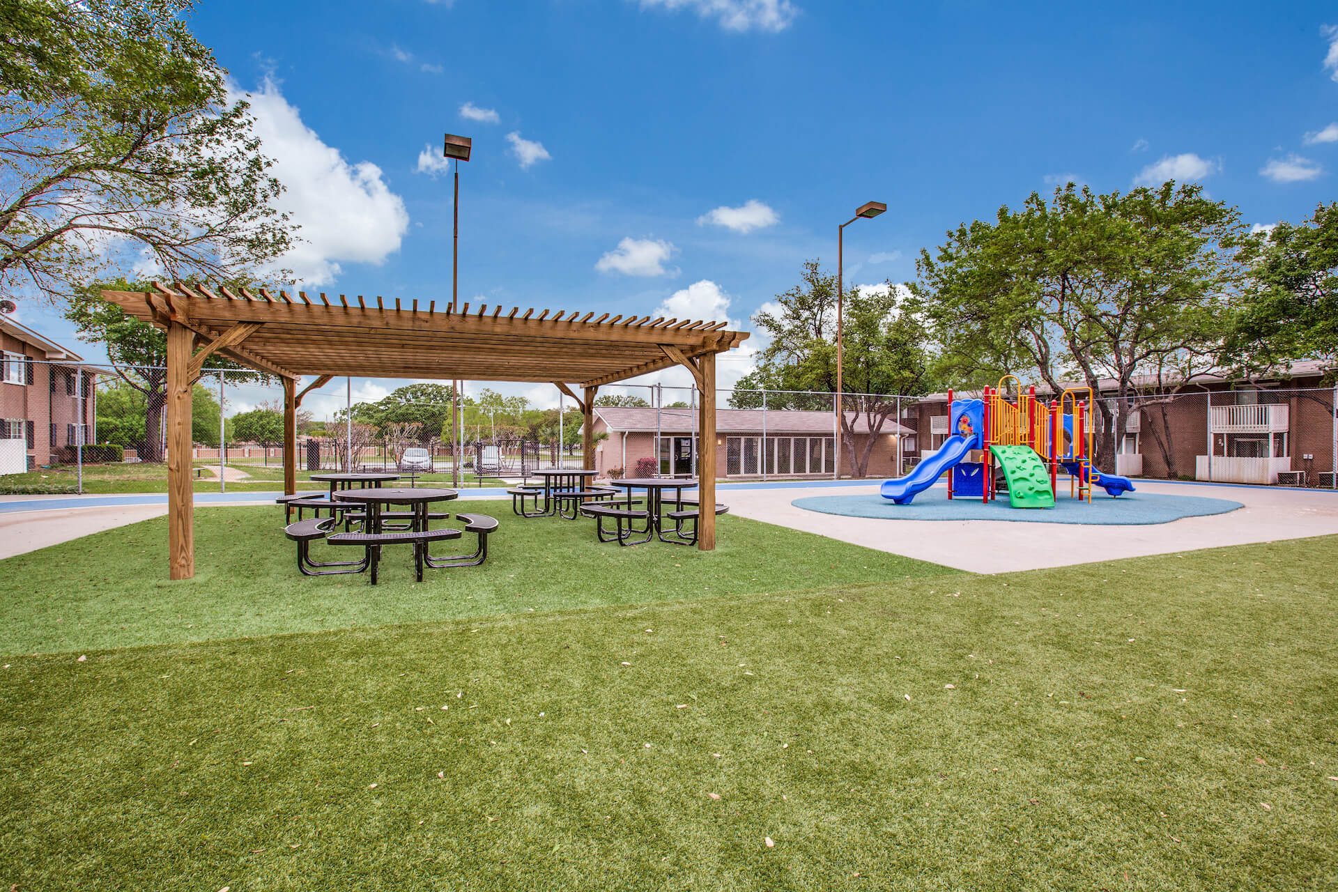 children's play structure and nearby tables with seats under a veranda